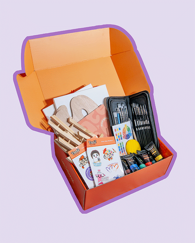 Angled view of Date in a Crate Painting Crate on a lavender background with a purple outline, featuring two easels, two wooden paint palettes, a painting guide, a zippered paintbrush set, acrylic paint tubes, a color wheel chart, a yellow mixing sponge, and themed paint date stickers.