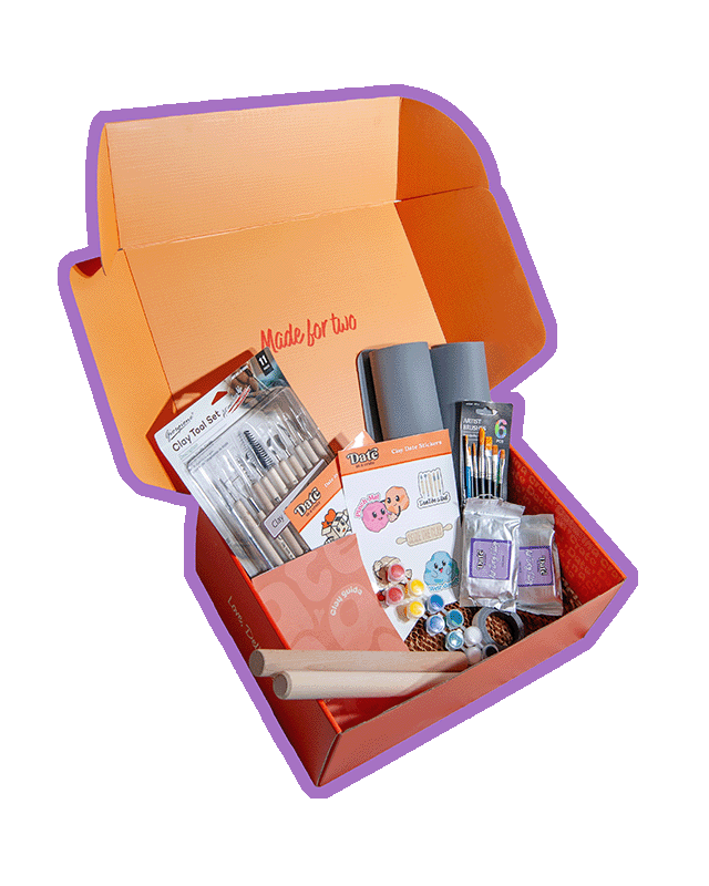 Angled view of Date in a Crate Clay Crate on a lavender background with a purple outline, showing clay tool set, grey silicone mats, paintbrushes, paint pots, wooden rolling pins, clay guide, clay-themed stickers, two packs of 250g air dry clay, and magnet tape.